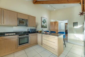 A modern kitchen with wooden cabinets, a built-in oven, a microwave, and a coffee maker.