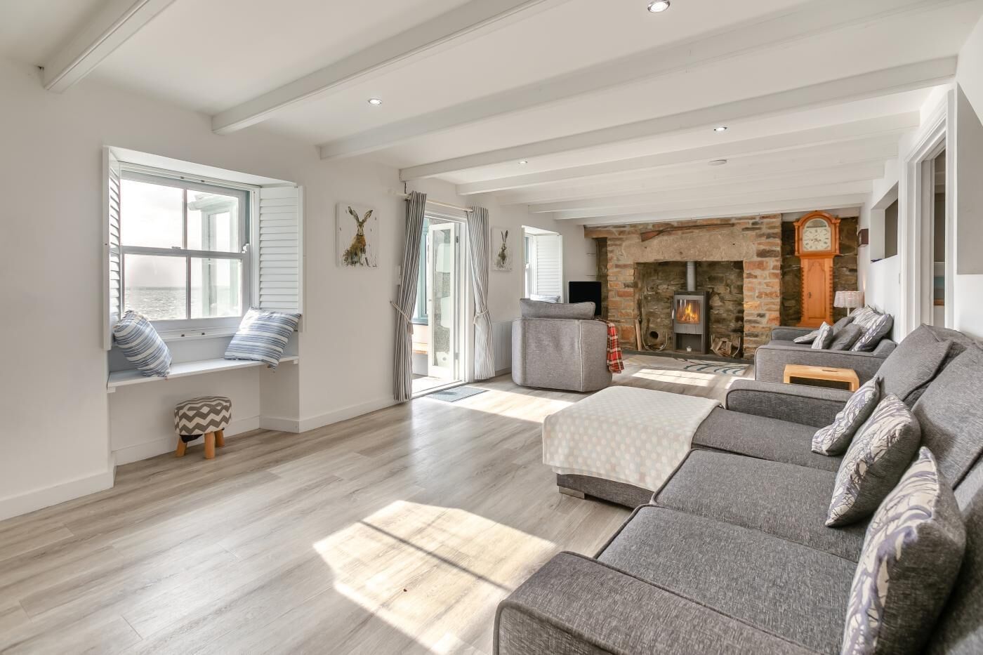 A spacious living room with a fireplace, a sofa set, and a window with blinds.