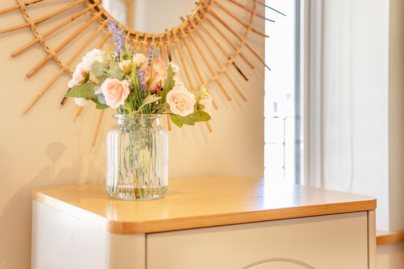 A clear glass vase with flowers on a wooden surface.