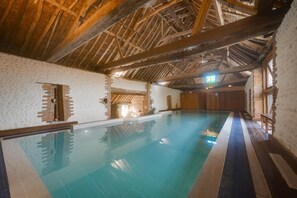 An indoor swimming pool with a wooden ceiling and brick walls. - 6 Bed in Bacton (oc-1836) (Bacton)
