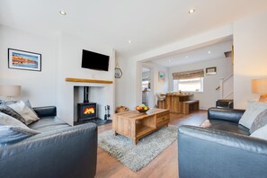 A modern living room with a fireplace, leather sofas, a wooden coffee table, and a TV mounted on the wall. - 3 Bed in Docking (oc-1837) (Docking)