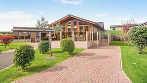 A modern building with a large glass entrance, a brick pathway leading to the entrance, and well-maintained greenery. - 3 Bed in Whitby (oc-wa057) (Runswick Bay)