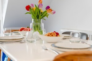 A dining table with plates, cutlery, and a vase of tulips. - 2 Bed in Padstow (oc-p00655) (Padstow)