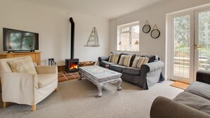 A cozy living room with a fireplace, a television, and comfortable seating. - 3 Bed in Sedgeford (oc-1827) (Sedgeford)