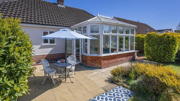 A conservatory with a glass roof, a patio table with chairs, and a brick wall. - 2 Bed in Snape (oc-12sf) (Snape)