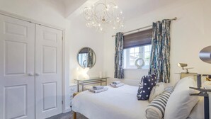 A bedroom with a bed, bedside tables, a mirror, a chandelier, curtains, and a window. - 2 Bed in Snape (oc-12sf) (Snape)