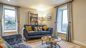 Un salon avec un canapé bleu, une table basse ronde et un tapis à motifs.