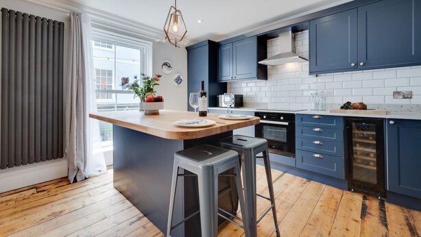 Une cuisine moderne avec des meubles bleus, un îlot central en bois et un four encastré.