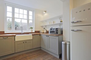Una cocina con ventana, microondas, tostadora y refrigerador.