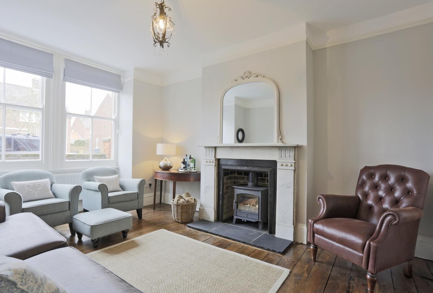 Un salon avec une cheminée, deux fauteuils, un canapé et un tapis.