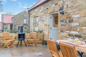 A stone building with a patio area featuring a grill, wooden chairs, and a table set for breakfast. - 2 Bed in Castleton (oc-f34013) (Castleton)