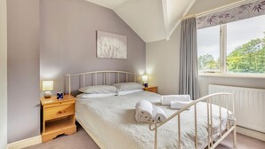 A bedroom with a bed, nightstands, a lamp, a window with curtains, and a radiator. - 2 Bed in Nr. Newby Bridge (oc-ld168) (Backbarrow)