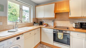 A compact kitchen with a window, a sink, a stove, and a microwave. - 2 Bed in Nr. Newby Bridge (oc-ld168) (Backbarrow)