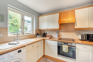 A compact kitchen with a window, a sink, a stove, and a microwave. - 2 Bed in Nr. Newby Bridge (oc-ld168) (Backbarrow)