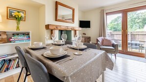 A dining area with a table set for four, a bookshelf, a mirror, and a TV. - 2 Bed in Nr. Newby Bridge (oc-ld168) (Backbarrow)