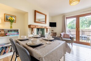 A dining area with a table set for four, a bookshelf, a mirror, and a TV. - 2 Bed in Nr. Newby Bridge (oc-ld168) (Backbarrow)