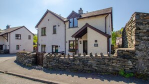 A row of traditional stone houses with a stone wall in front, a clear sky, and a paved road. - 2 Bed in Nr. Newby Bridge (oc-ld168) (Backbarrow)