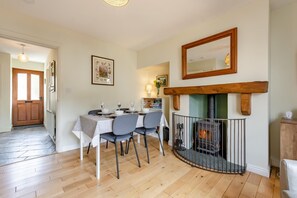 A dining area with a table set for four, a fireplace, and a hallway leading to a door. - 2 Bed in Nr. Newby Bridge (oc-ld168) (Backbarrow)