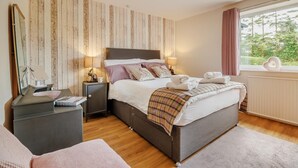 A bedroom with a large bed, bedside tables, a dresser, a mirror, and a window with a view of greenery. - 3 Bed in Bala (oc-bow26) (Parc)