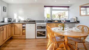 Una cocina moderna con armarios de madera, horno empotrado, microondas y un comedor con mesa y sillas de madera.