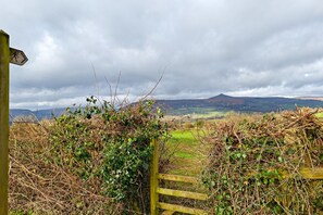 Un paysage rural avec une barrière en bois et un panneau indiquant un sentier de randonnée.