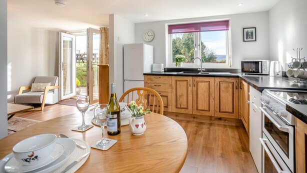 Una cocina moderna con armarios de madera, un comedor con una mesa redonda y vistas al exterior a través de una ventana.