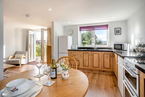 Una cocina moderna con armarios de madera, un comedor con una mesa redonda y vistas al exterior a través de una ventana.