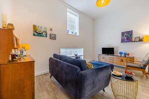 A modern living room with a sofa, TV, wooden cabinet, and artwork on the walls. - 1 Bed in Cromer (oc-1844) (Cromer)