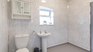 Un baño con inodoro, lavamanos, ventana y armario.