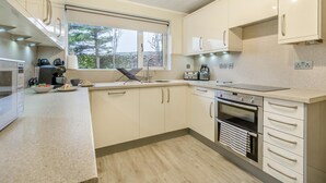 Een moderne keuken met een ingebouwde oven, een koffieapparaat en een waterkoker.
