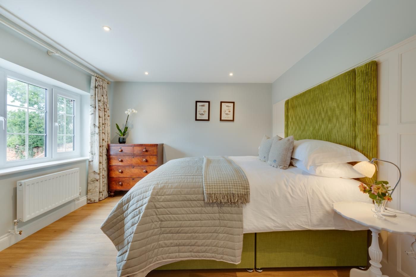 A bedroom with a bed, a dresser, a radiator, and a window.