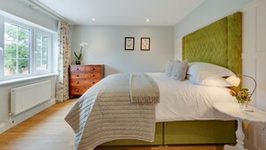 Un dormitorio con cama, cómoda, radiador y ventana.