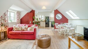 Um apartamento loft aconchegante com sofá vermelho, área de jantar, cozinha e uma janela grande.