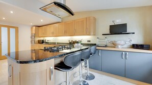 Une cuisine moderne dotée d’un îlot central, de tabourets de bar, d’un téléviseur à écran plat et d’une tête de cerf décorative.