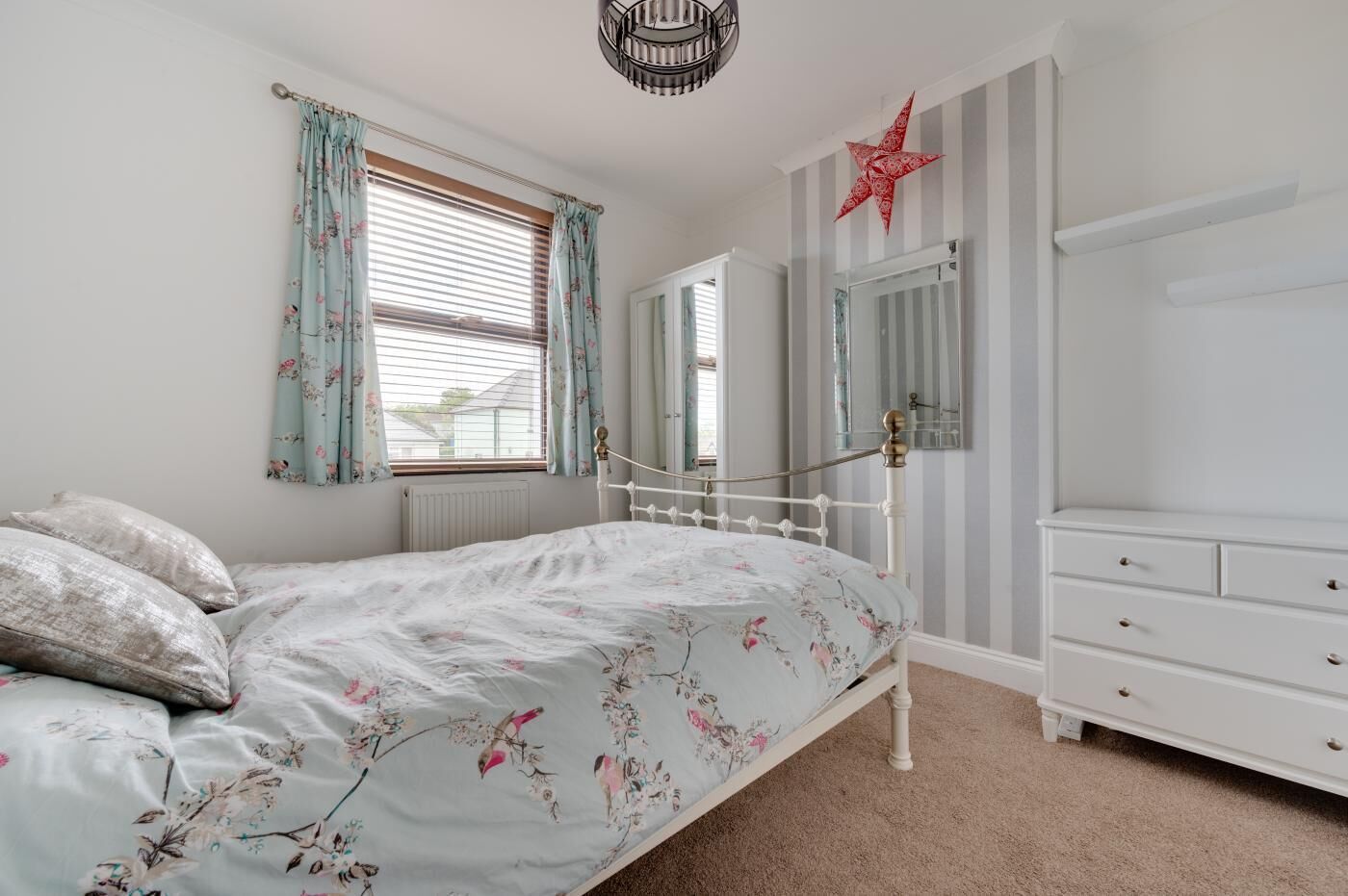 A bedroom with a bed, a dresser, a mirror, and a star decoration on the wall.