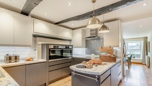 Una cocina moderna con una isla central, hornos integrados y un comedor con vistas.