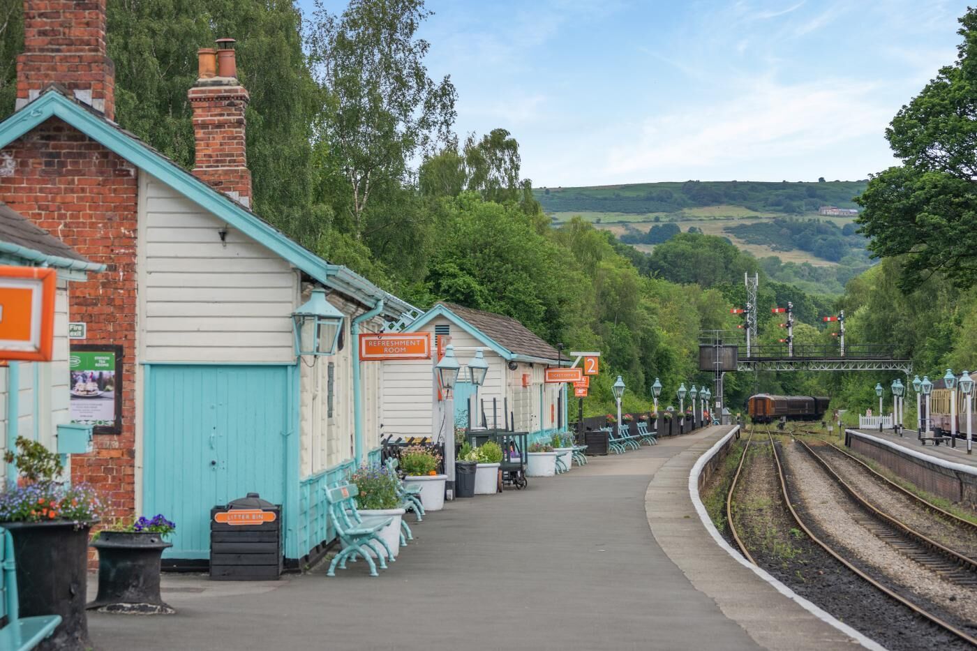 A train station platform with a refreshment room, benches, and a railway track.