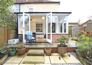 A house with a glass door leading to a patio, a chair, and potted plants. - 2 Bed in Halesworth (oc-cpl) (Halesworth)