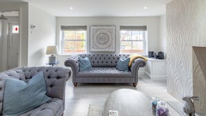 A living room with a grey sofa, two armchairs, a lamp, and a decorative wall panel. - 1 Bed in Holt (oc-1854) (Holt)