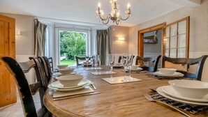 Ein Esszimmer mit einem großen Holztisch, gedeckt für sechs Personen, umgeben von Stühlen.