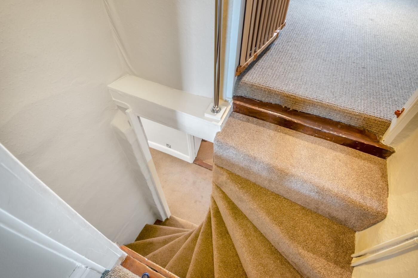A carpeted staircase with a handrail and a carpeted landing.