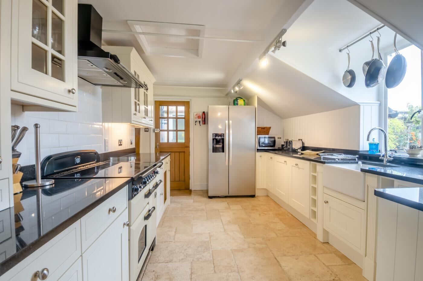 Una cocina moderna con armarios blancos, estufa de acero inoxidable, refrigerador y microondas.