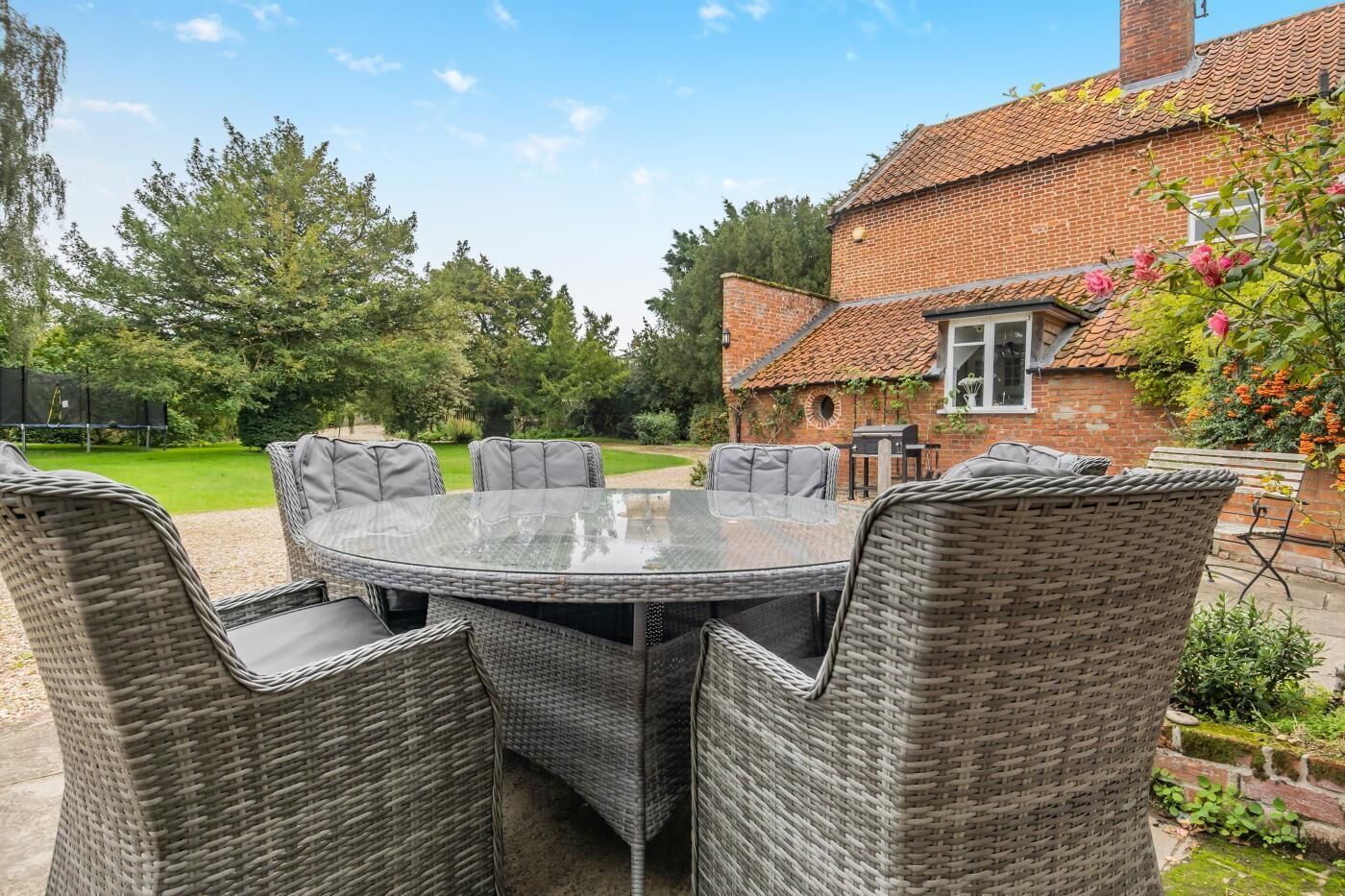 A round glass table with wicker chairs in an outdoor patio area.
