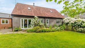 Ett tvåvåningshus med ett tak täckt av tegelpannor, en ytterdörr och en liten trädgård.