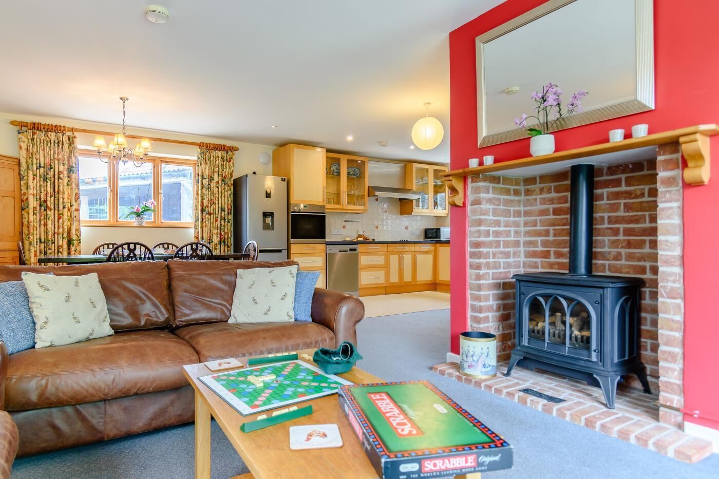 A cozy living room with a brown leather sofa, a Scrabble board, and a fireplace.