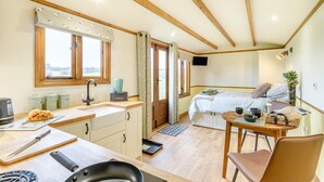 A compact kitchen with a sink, a dining area with a table and chair, a bed with a view, and a small TV. - 1 Bed in Farnsfield (oc-s34109) (Farnsfield)