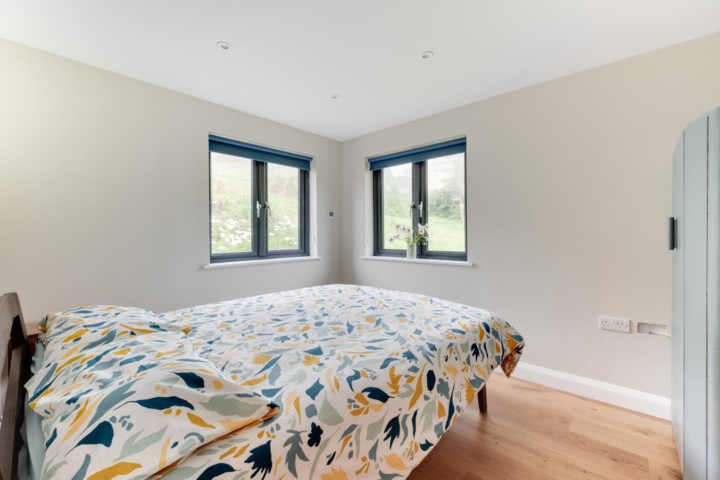 Ein Schlafzimmer mit einem Bett, zwei Fenstern und Holzboden.