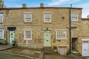 A stone building with multiple windows, a green door, and a small porch area.