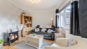 A living room with a fireplace, a sofa, a coffee table, and a bookshelf. - 1 Bed in Stepaside (oc-pw9268) (Amroth)