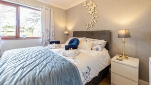 A neatly made bed with a blue and white duvet, two bedside lamps, a nightstand, and a wall-mounted butterfly decor. - 1 Bed in Stepaside (oc-pw9268) (Amroth)